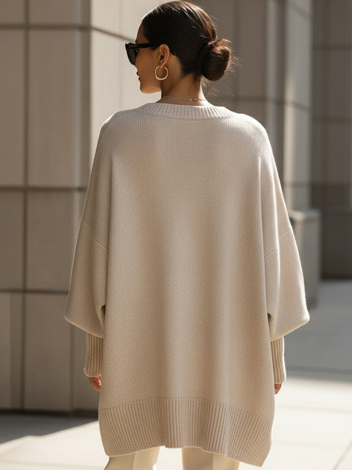Achterkant van de beige poncho gedragen door een model, met brede geribbelde onderrand 5