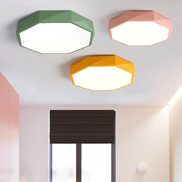 Drie achthoekige plafondlampen in groen, roze en geel aan een wit plafond bij een raam 1