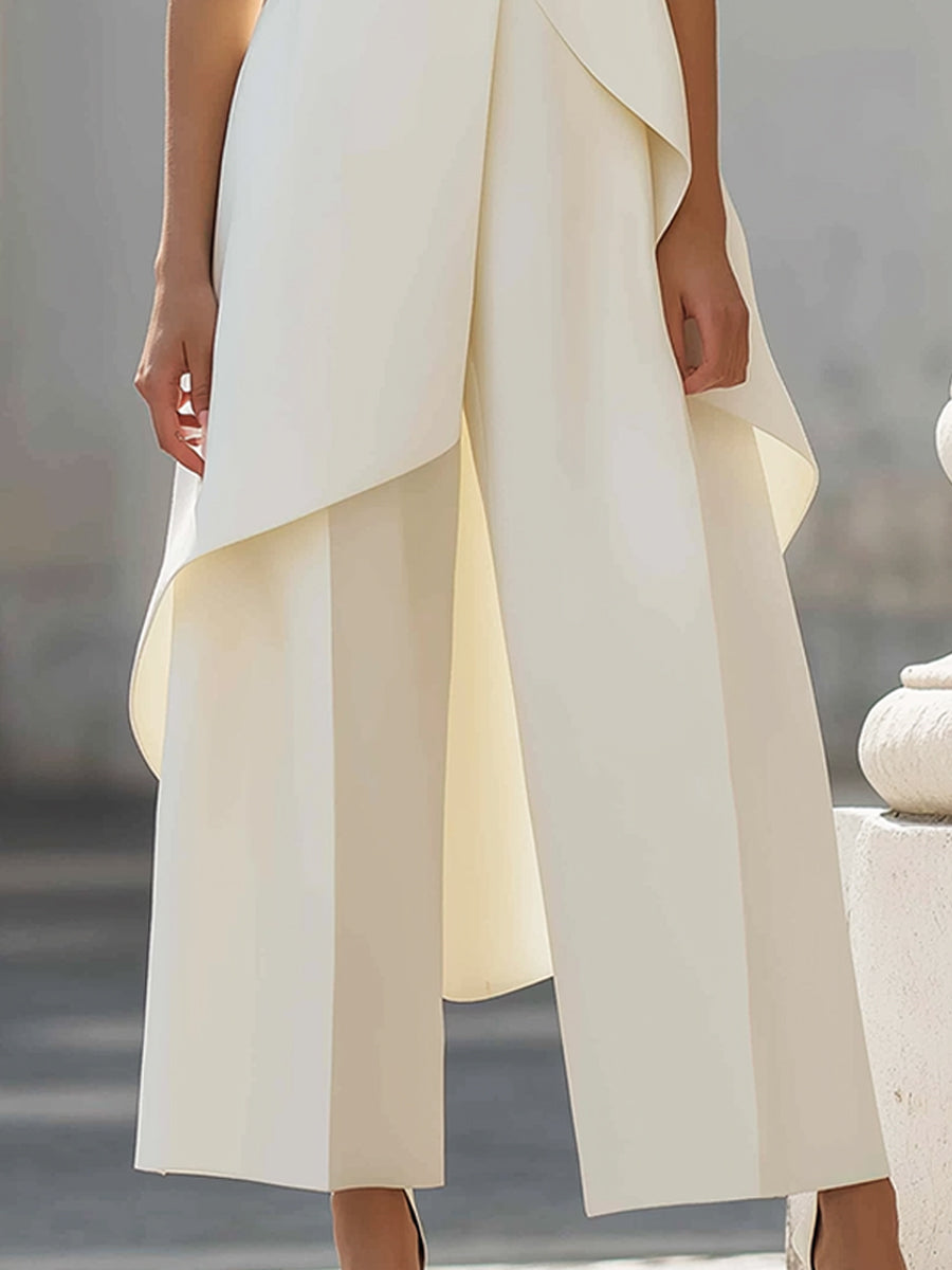 Close-up van de crèmewitte wijde broek met persplooi en de afhangende, asymmetrische zoom van de top. 12