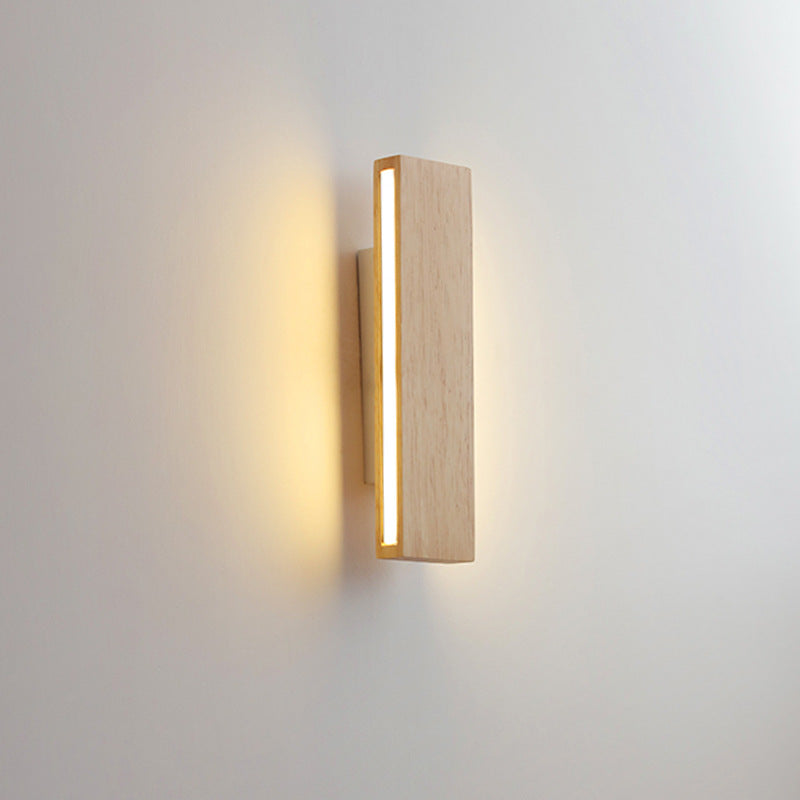 Brandende verticale houten wandlamp, schuin van opzij gezien, met een lichtstrip langs de zijkant en gloed op de muur. 10