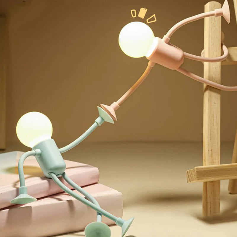 Groen en roze mannetjeslampje zittend en reikend naar elkaar bij een houten ezel, op een stapel boeken in warm licht. 6