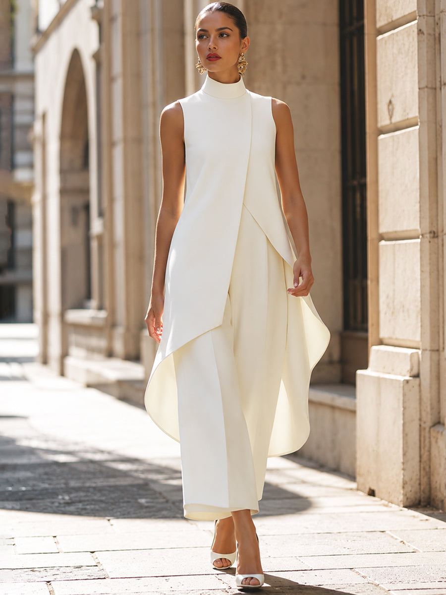 Model loopt in crèmewitte set met asymmetrische top langs een zandkleurig gebouw met boogvormige ingang. 9