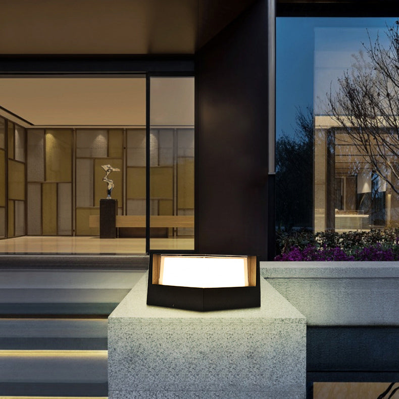 Zwarte lamp met warm verlicht scherm op een betonnen pilaar voor een modern huis met glazen gevel. 3