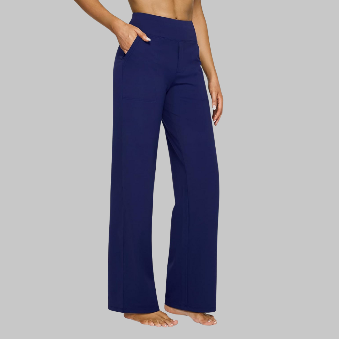 Model in donkerblauwe broek met hoge taille en rechte pijp, zijaanzicht met een hand in de zak. 12