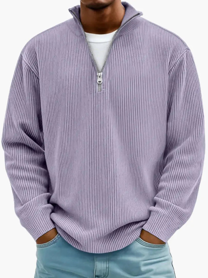 Model draagt de geribbelde trui met kwartrits in lila, met een wit shirt eronder en handen in de broekzakken. 9