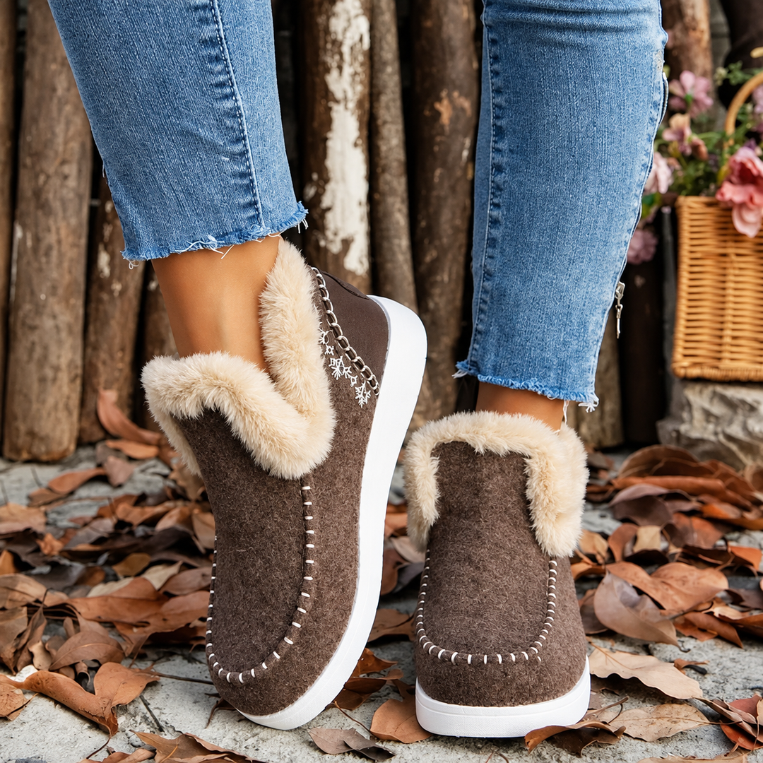 Bruine instapsneakers met beige pluchen kraag en witte stiksels, gedragen door een model, bovenaanzicht van voor en schuin achter. 2