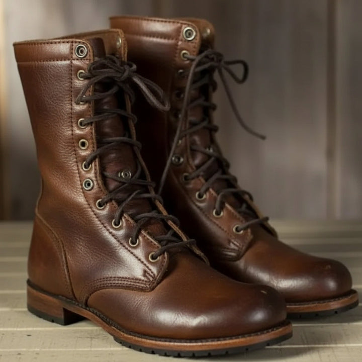 Paar bruine leren veterlaarzen met donkere veters en metalen oogjes, schuin van voren gefotografeerd op een houten ondergrond. 1
