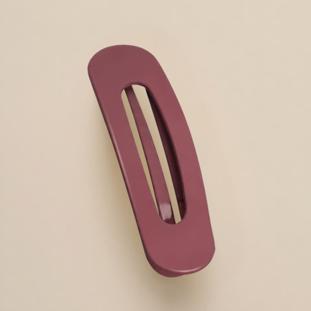 Matte bordeauxrode haarclip met ovale opening, schuin van boven gefotografeerd op een beige achtergrond 13