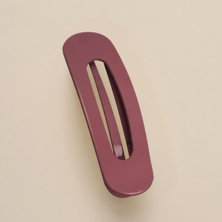 Matte bordeauxrode haarclip met ovale opening, schuin van boven gefotografeerd op een beige achtergrond 13