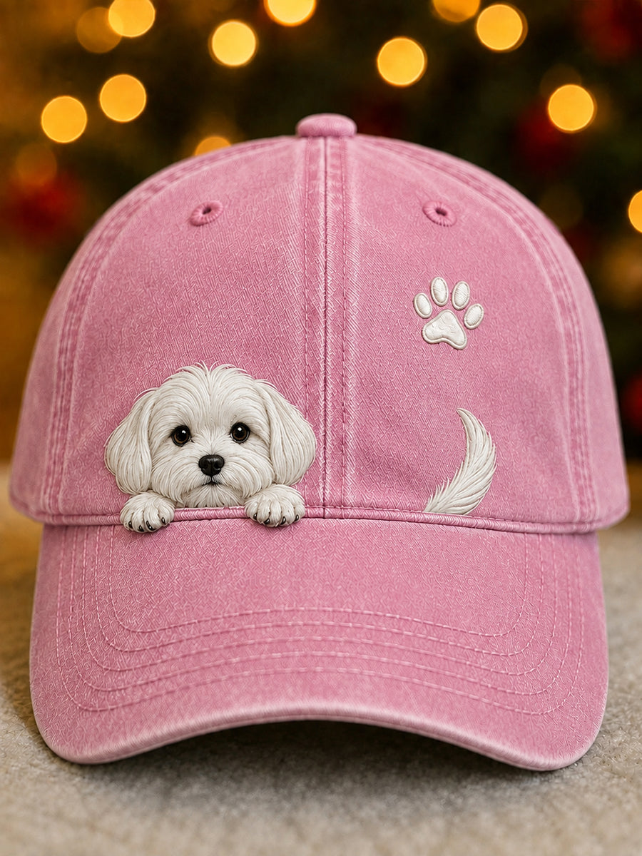 Voorkant van de baseballpet in roze met een wit geborduurd hondje, pootafdruk en staartje, voor lichtjes op de achtergrond 2
