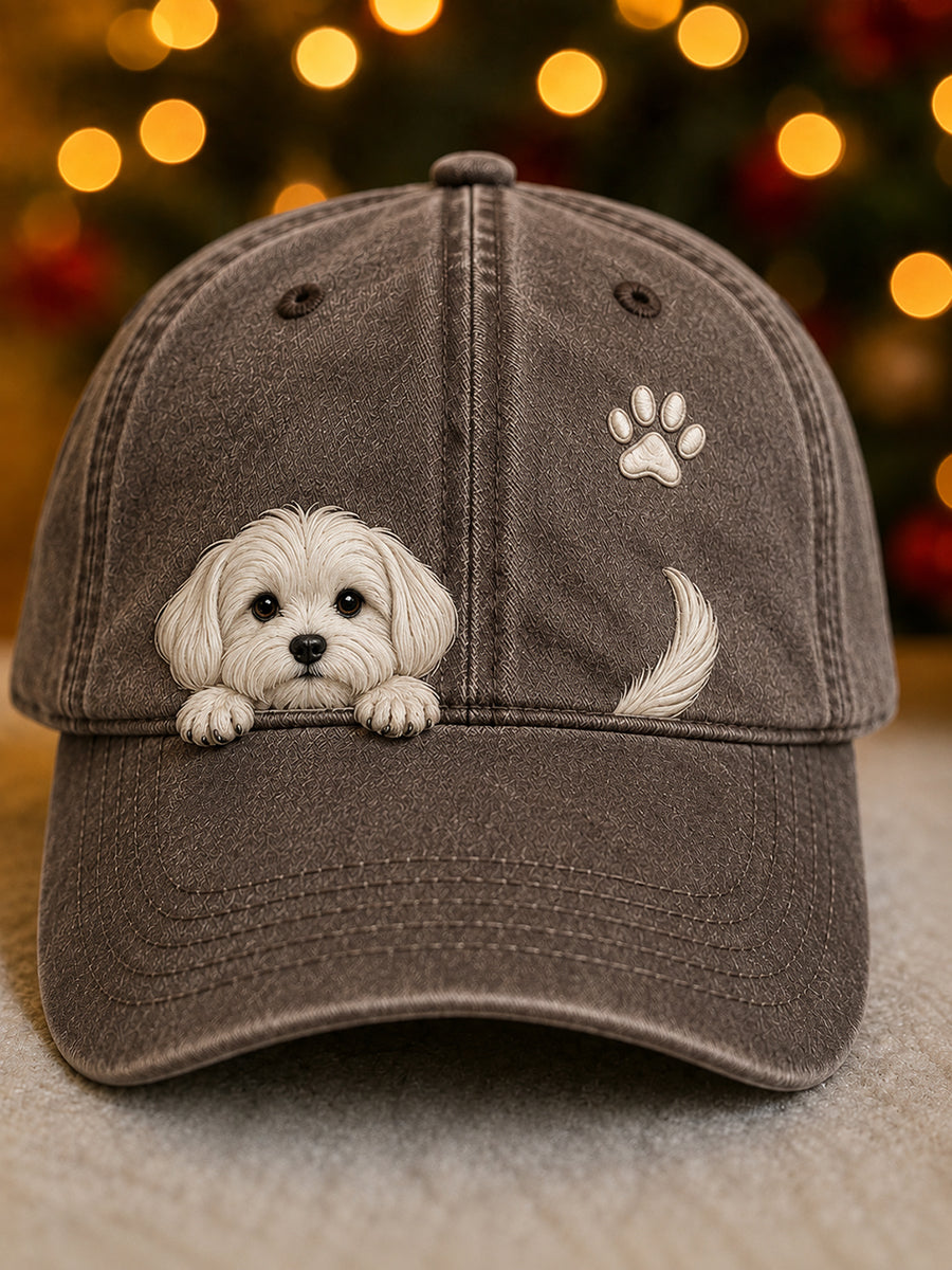 Voorkant van de baseballpet in bruingrijs met een wit geborduurd hondje, pootafdruk en staartje, voor een wazige kerstachtergrond 6