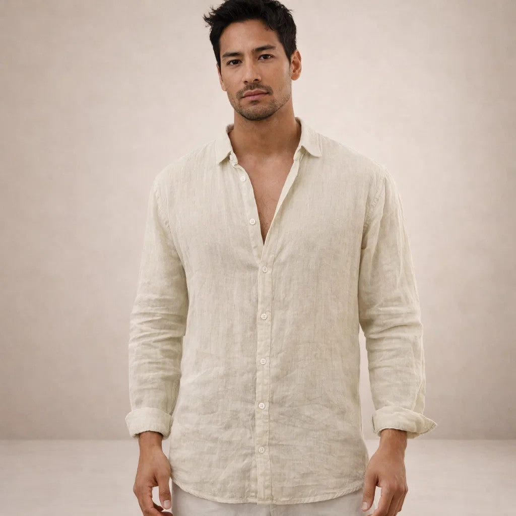Model kijkt in de camera en draagt een beige linnen overhemd met kraag, opgerolde mouwen en een lichte broek. 11