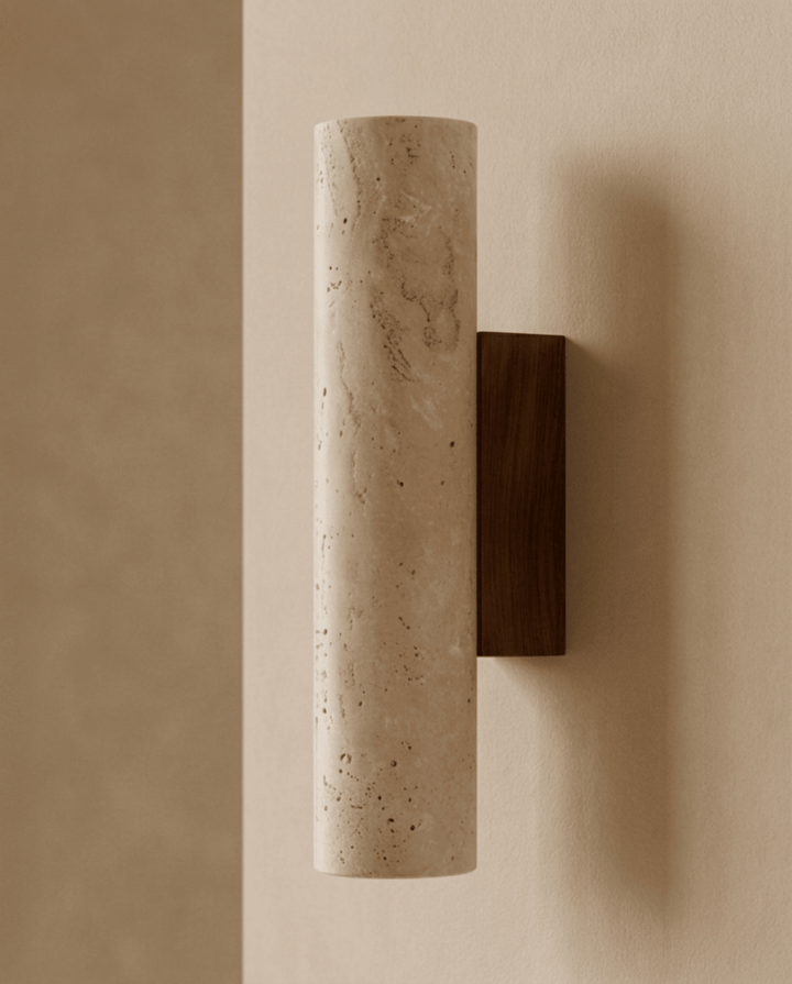 Cilindervormige travertijnen wandlamp met houten wandplaat, schuin van opzij gezien tegen een warme beige muur 1