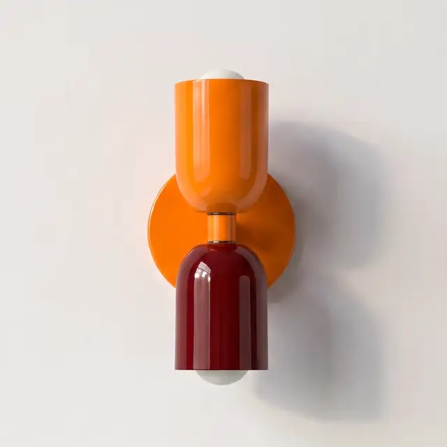 Wandlamp met een oranje bovenkap en een glanzende bordeauxrode onderkap op een oranje ronde montageplaat. 25
