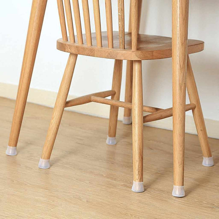 Houten stoel op een lichte houten vloer met doorschijnende siliconen dopjes onder alle poten, tegen een witte muur. 5