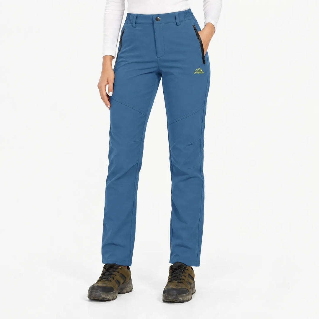 Model draagt de broek in middenblauw met ritszakken, schuine naden en wandelschoenen, vooraanzicht 8