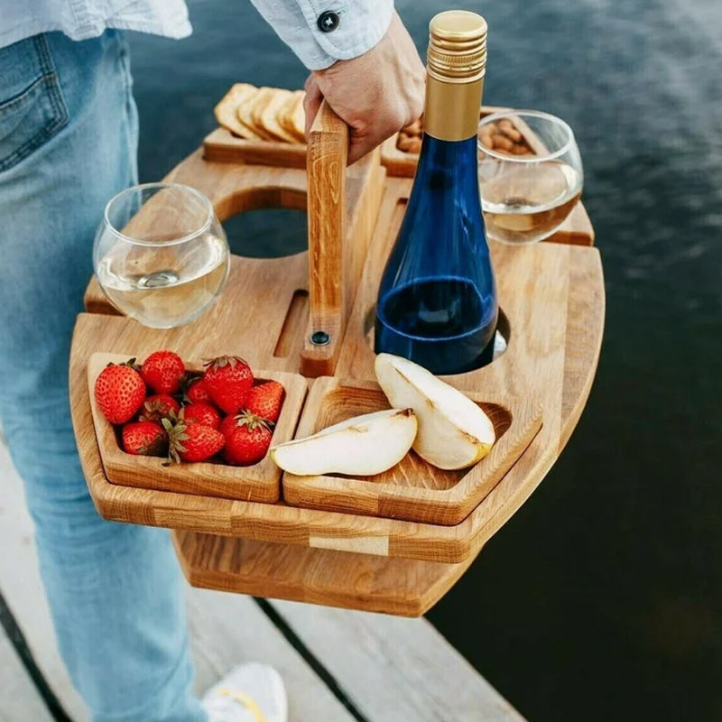 Persoon draagt de gevulde wijntafel aan het houten handvat, met fles, glazen, aardbeien en peer 4
