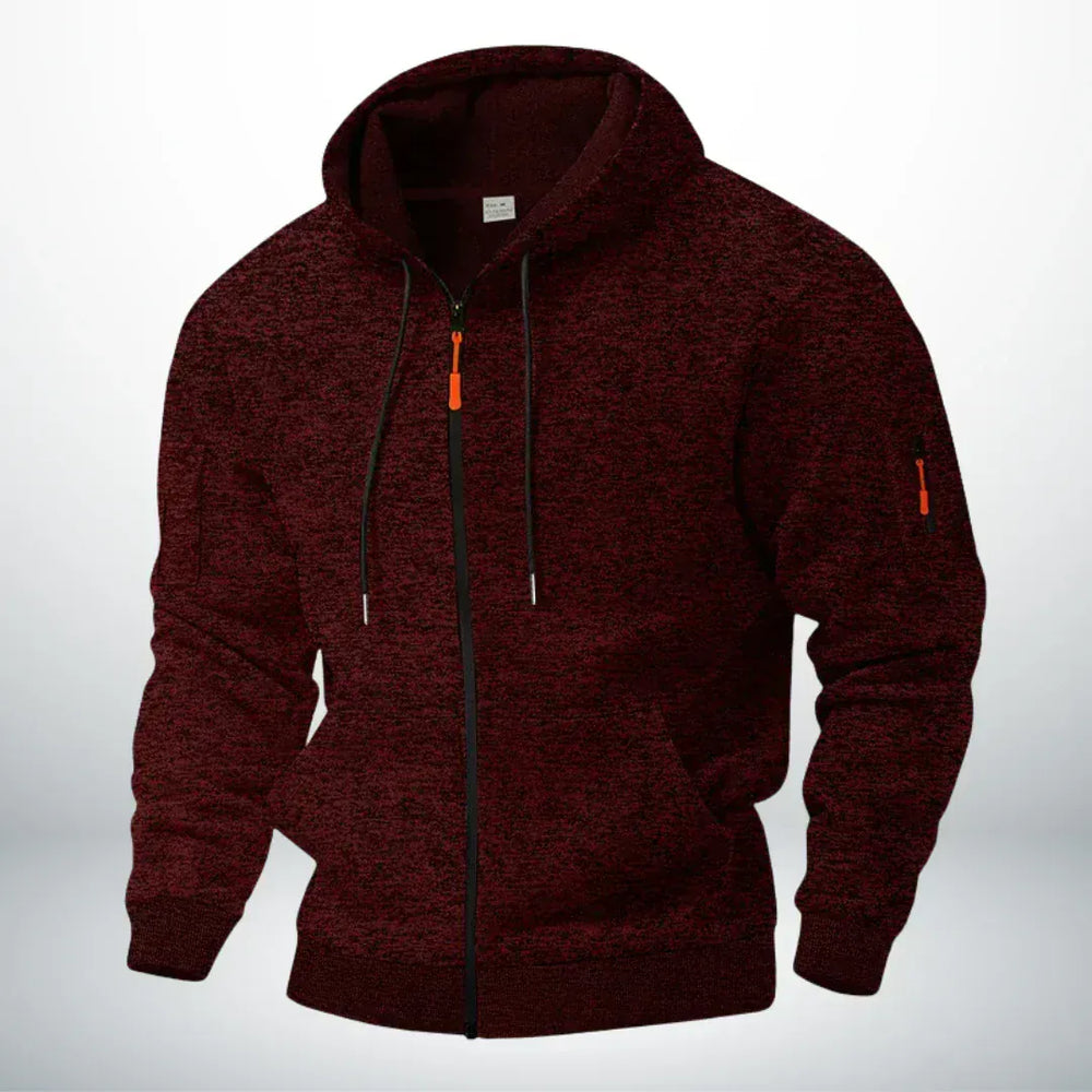 Dezelfde hoodie in gemêleerd donkerrood, schuin van voren gefotografeerd met zichtbare ritszak op de mouw en oranje trekker. 2