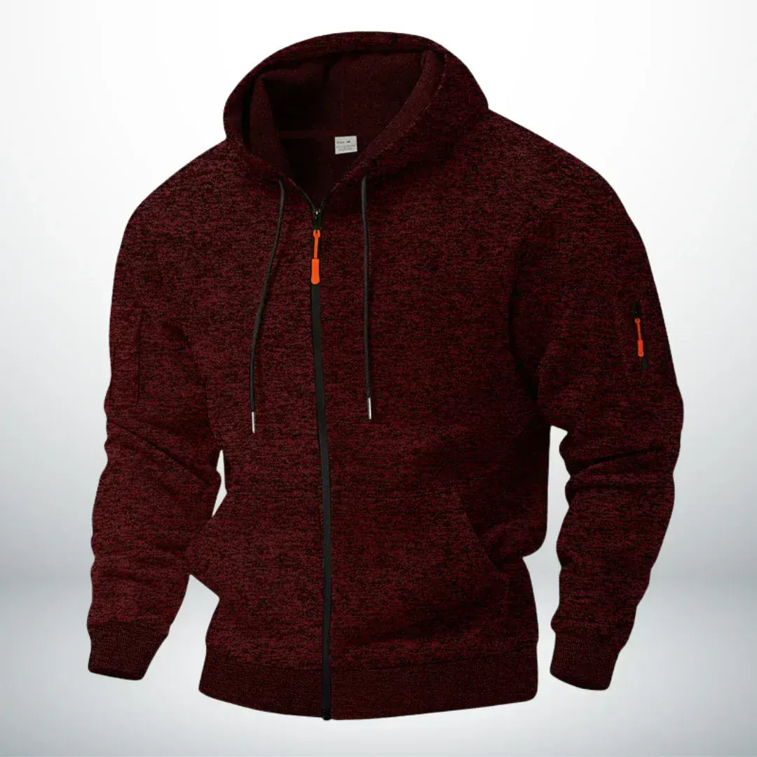 Dezelfde hoodie in gemêleerd donkerrood, schuin van voren gefotografeerd met zichtbare ritszak op de mouw en oranje trekker. 2