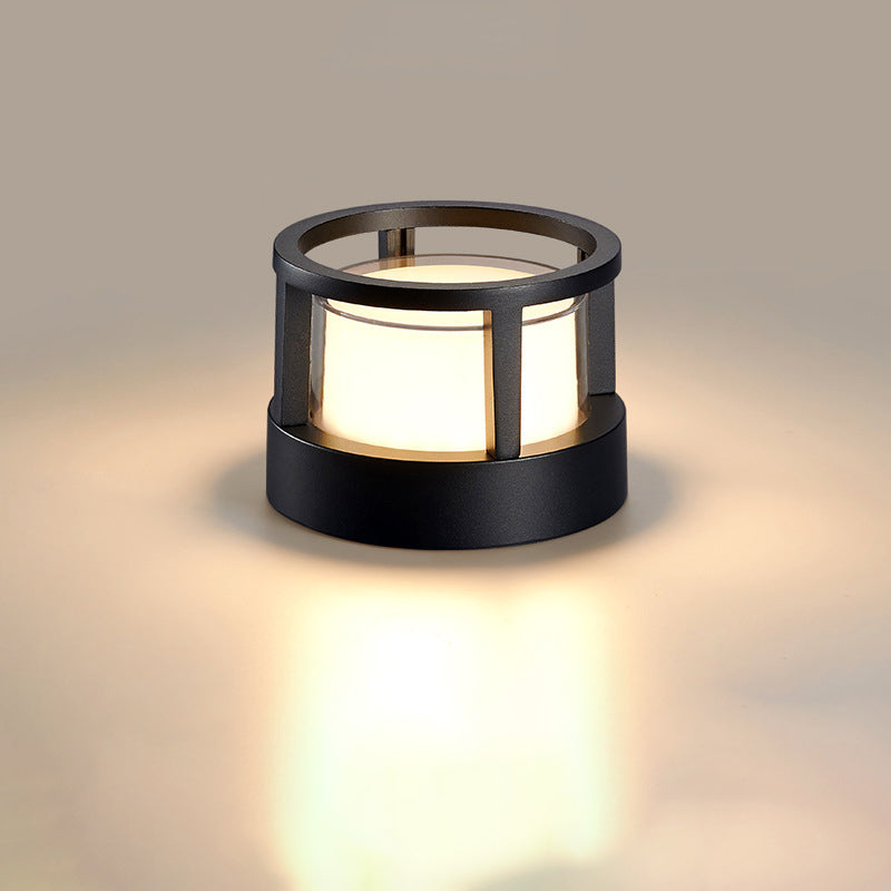 Ronde zwarte lamp met open ringvormige bovenkant, waardoor het gloeiende glas zichtbaar is, op neutrale achtergrond. 9