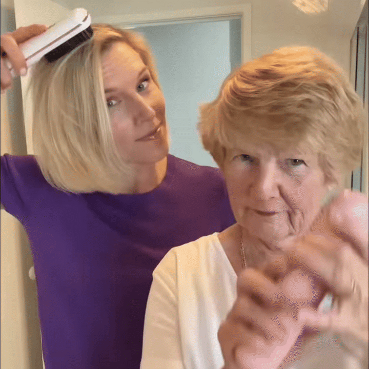 Blonde vrouw in paars shirt stylt haar haar met een witte borstel, naast een oudere vrouw met kort haar. 9