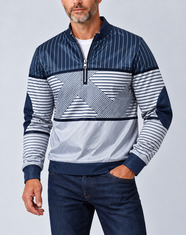 Man met grijze baard draagt de marineblauw-witte gestreepte pullover met halve ritssluiting, een witte trui eronder en een donkere spijkerbroek, voorkant. 1