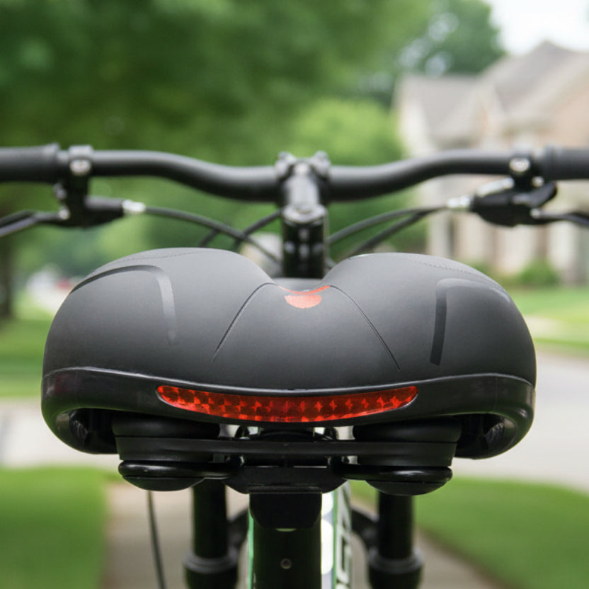 Achteraanzicht van het zwarte fietszadel op een fiets, met een rode reflecterende strip en wazig stuur en straat erachter. 2