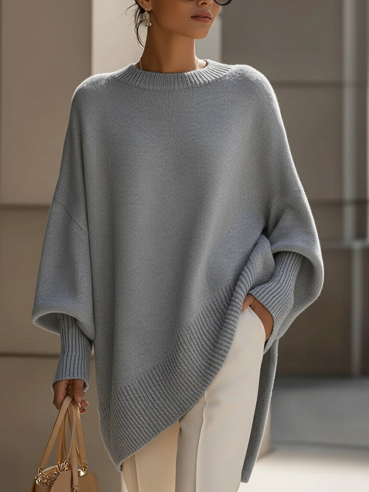 Model draagt de grijze poncho met wijde mouwen en geribbelde afwerking, hand in de zak 10