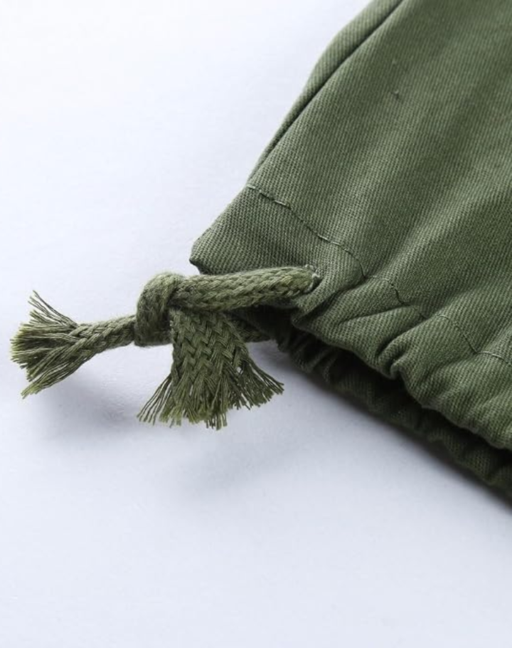 Close-up van het koordje met knoop en uitgerafelde uiteinden aan de pijpzoom van de legergroene cargobroek. 12