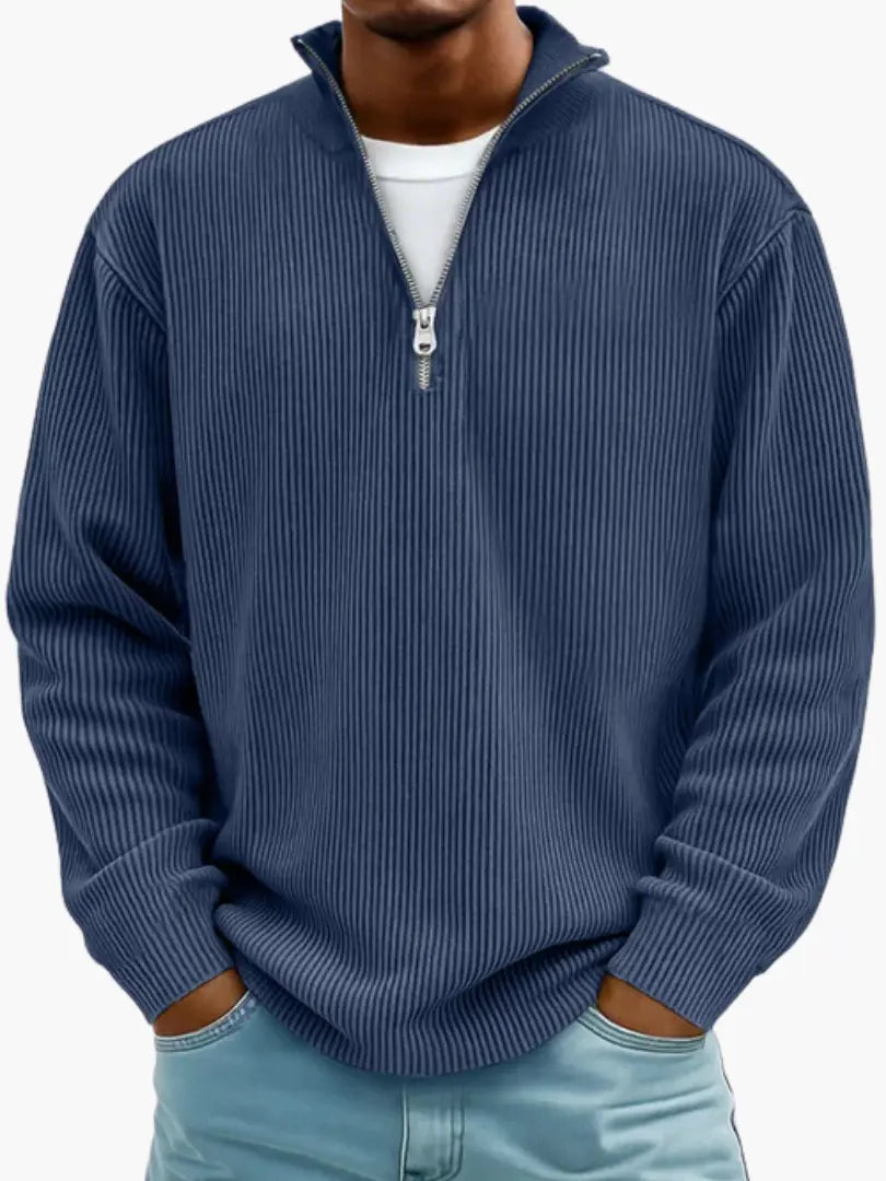 Model draagt de geribbelde trui met kwartrits in donkerblauw, met een wit shirt eronder en handen in de zakken. 5