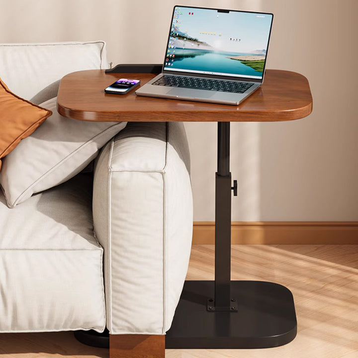 Bruin laptopbureau waarvan het blad over de armleuning van een bank uitsteekt, met laptop en telefoon erop. 11