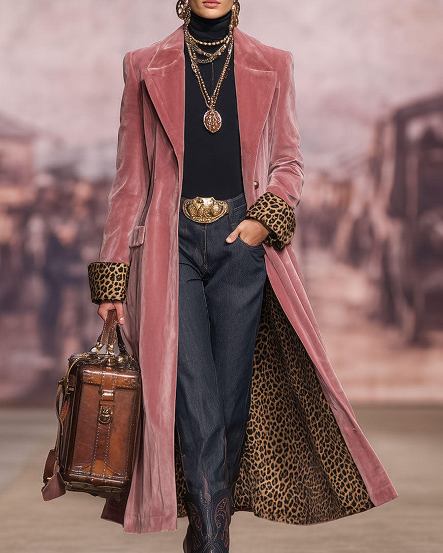 Model op een catwalk met vage stadsachtergrond draagt de roze fluwelen mantel met luipaardmanchetten, een hand in de zak en een leren tas. 3