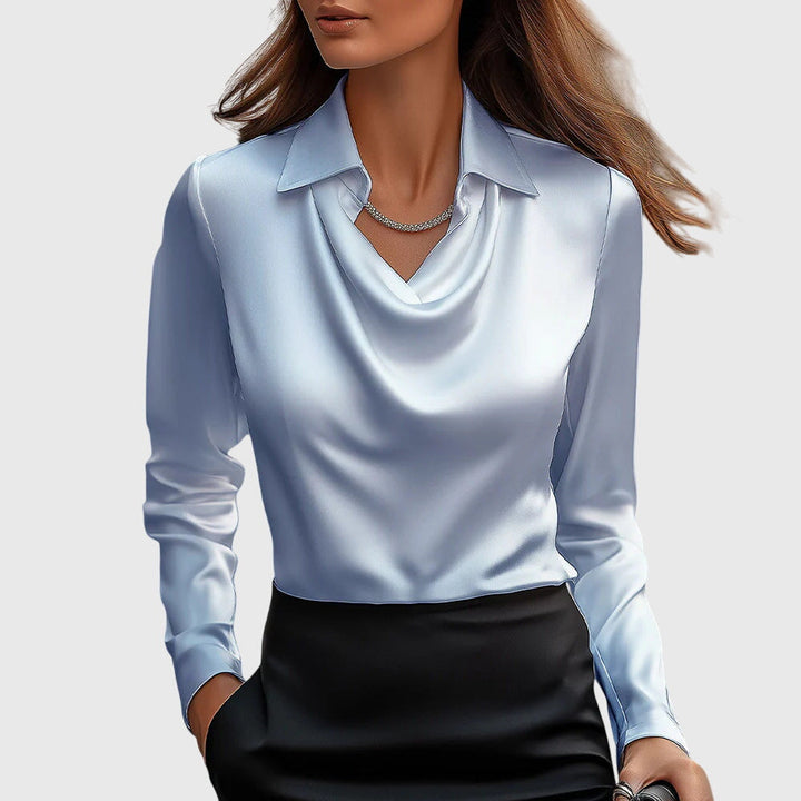 Model draagt de lichtblauwe satijnen blouse met gedrapeerde hals en lange mouwen, gecombineerd met een zwarte rok. 4