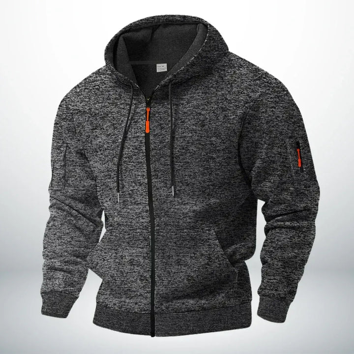 Hoodie in gemêleerd donkergrijs met capuchon, zwarte rits en oranje details, schuin van voren op een neutrale achtergrond. 5