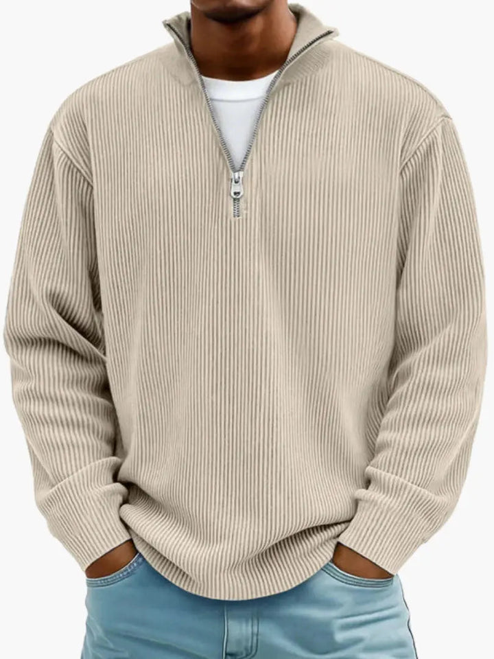 Model draagt de geribbelde trui met kwartrits in beige, met een wit shirt eronder en lichtblauwe spijkerbroek. 4