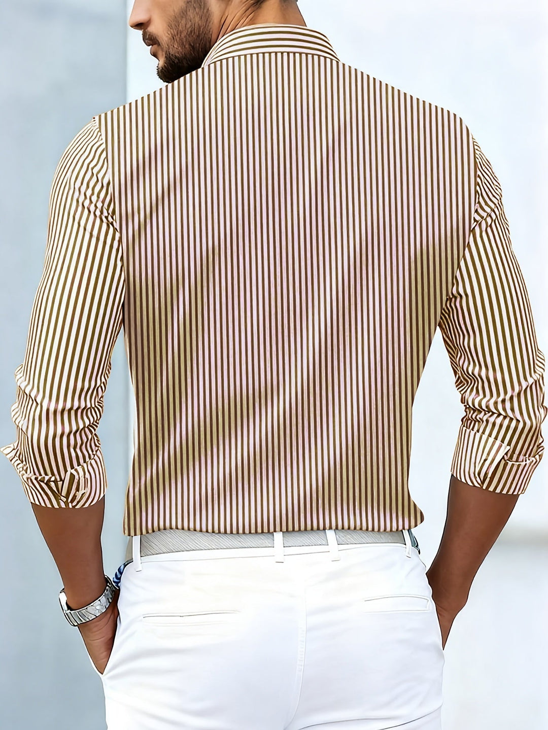 Achterkant van het bruin-beige gestreepte overhemd, gedragen door een man met witte broek, met doorlopende verticale strepen. 6