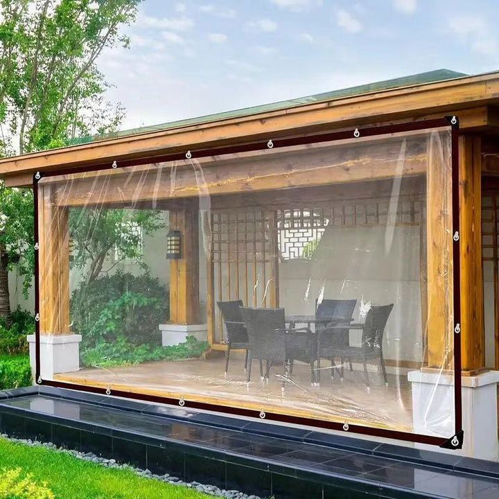 Doorzichtig zeil als windscherm gespannen voor een houten overkapping met tuinstoelen en tafel, bevestigd met ogen langs de rand. 3