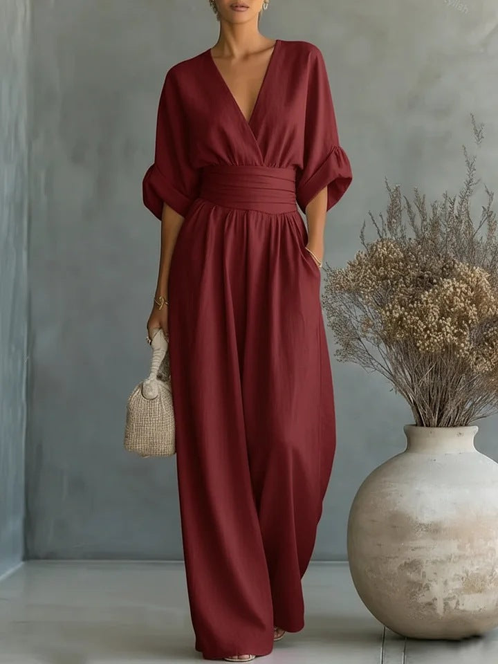 Dezelfde jumpsuit in wijnrood, frontaal gedragen met brede taille, wijde pijpen en rieten tasje in de hand. 4