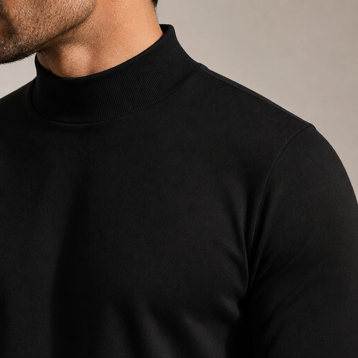 Close-up van de hoge ribgebreide kraag en schouder van het zwarte shirt, gedragen door een man. 6
