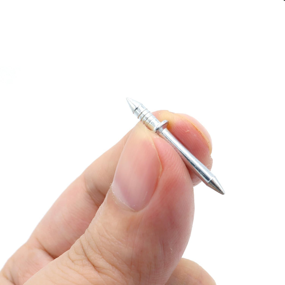 Een dubbelpuntige metalen nagel met geribbeld uiteinde en kraagje, tussen duim en vinger vastgehouden voor een idee van de grootte. 4
