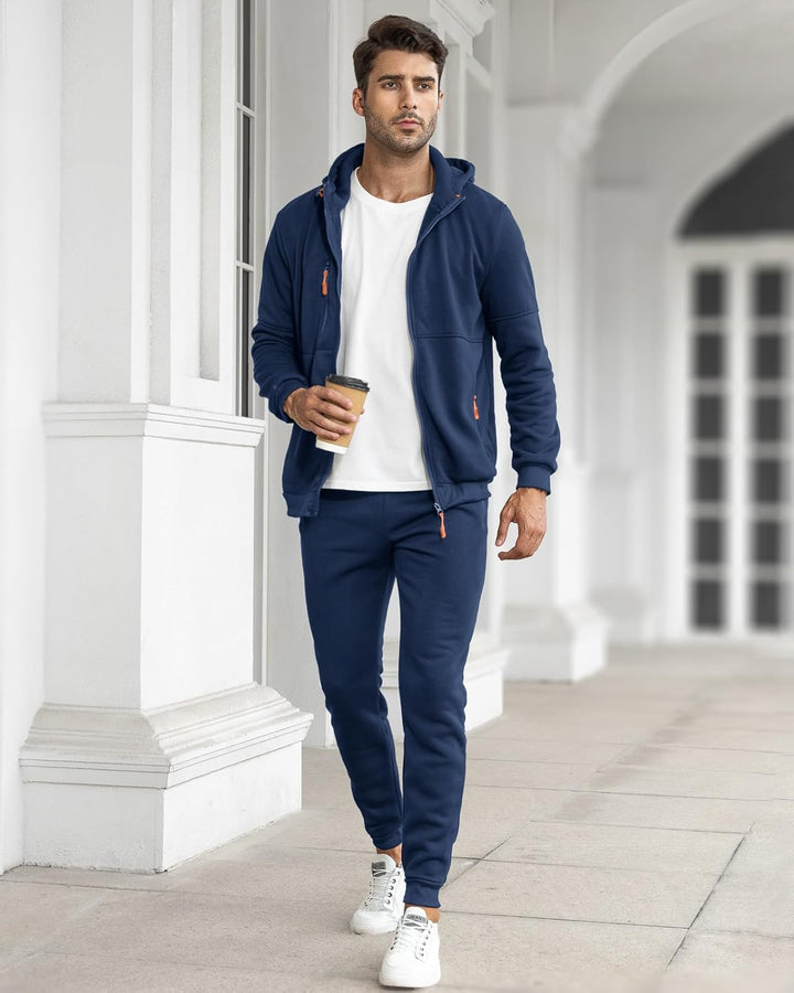 Model in donkerblauw trainingspak met open vest en wit shirt houdt een koffiebeker vast 4