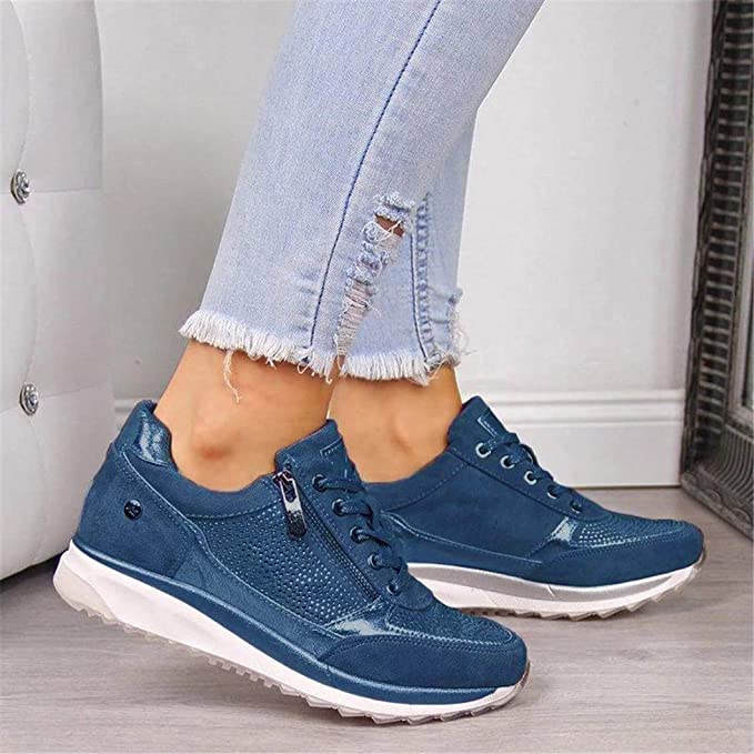Blauwe sneakers met rits en veters, gedragen met gescheurde lichtblauwe jeans, zijaanzicht van beide schoenen. 3