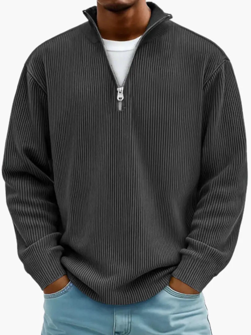 Model draagt de geribbelde trui met kwartrits in antraciet, met een wit shirt eronder en een lichtblauwe spijkerbroek. 7