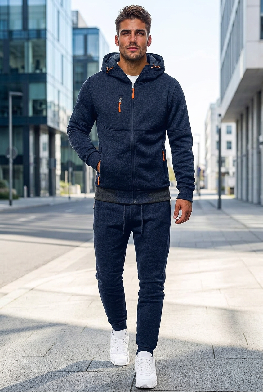 Man in donkerblauw trainingspak met capuchon en oranje ritsen wandelt door een stadsstraat 1
