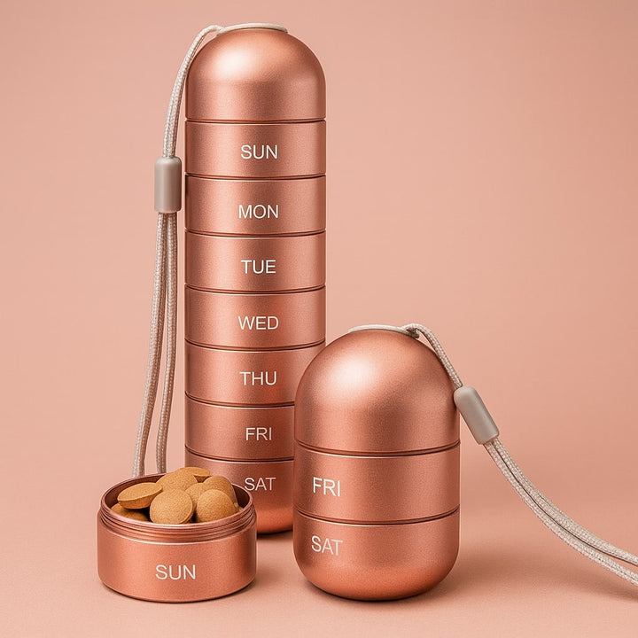 Roségouden aluminium pillendoos met koordje, volledig opgestapeld naast een los vakje met bruine tabletten en een korte stapel van twee vakjes. 1