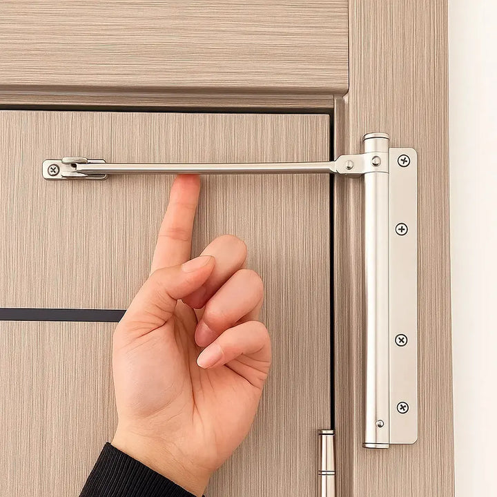 Zilverkleurige deursluiter gemonteerd op een lichte houten deur, met een hand die naar de arm wijst 1