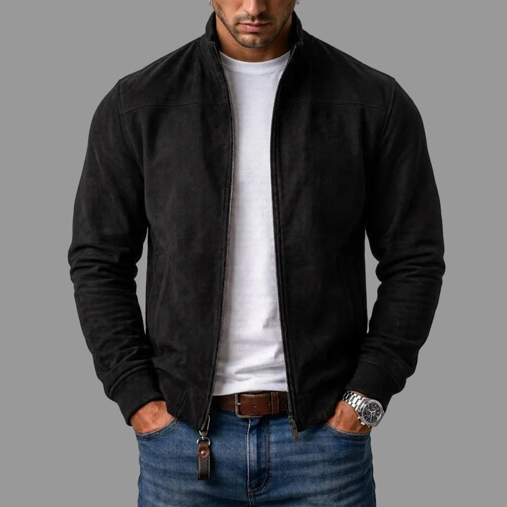 Model draagt de zwarte jack open over een wit t-shirt, met jeans, bruine riem en een leren sleutelhanger aan de rits. 1