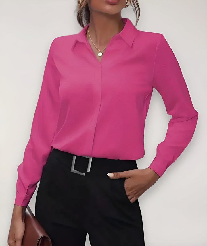 Felroze blouse gedragen door een model met zwarte broek, een hand in de zak 4
