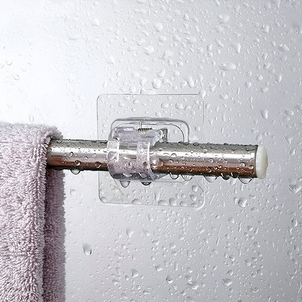 Doorzichtige klem houdt een metalen stang met een lila handdoek tegen een wand vol waterdruppels, bedoeld voor een vochtige badkamer. 4