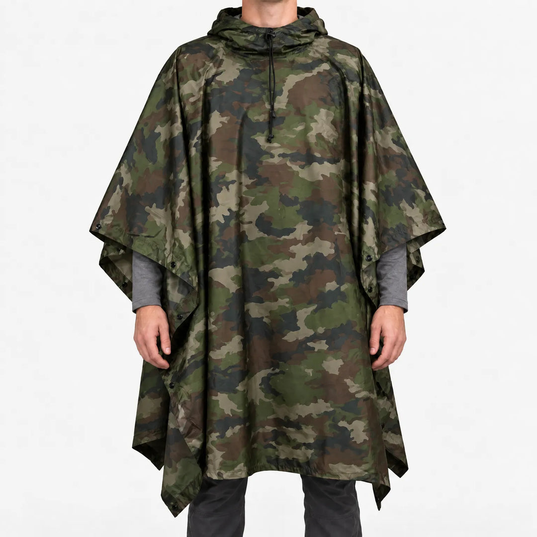 Voorkant van de poncho in klassieke woodland-camouflageprint met groene, bruine en zwarte vlekken, gedragen door een model op een witte achtergrond. 14